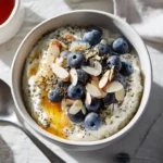 High-protein cottage cheese breakfast bowl topped with blueberries, chia seeds, almonds, and honey