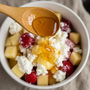 Drizzling honey and vanilla into cottage cheese fruit salad 