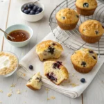 Golden cottage cheese muffins with blueberries cooling on a rack, recipe with cottage cheese, oats, and maple syrup