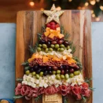 Christmas tree shaped charcuterie board with festive snacks and cheeses