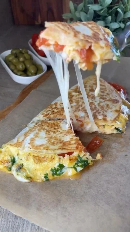 Delicious cheesy omelette served on a plate with fresh herbs